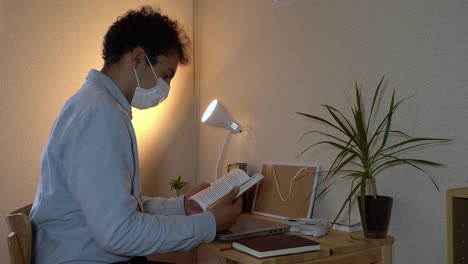 Ein-Mann-Mit-Gesichtsmaske,-Der-Während-Des-Ausbruchs-Des-Coronavirus-Ein-Buch-In-Seinem-Heimbüro-Liest---Nahaufnahme