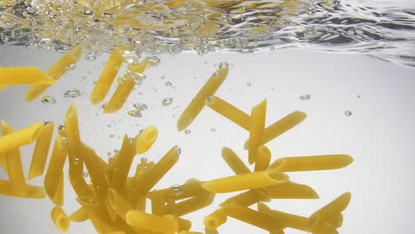 Pasta-noodles-slowly-sink-under-the-water-surface,-slow-motion,-close-up