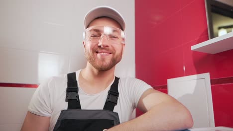 Professional-cleaner-wearing-goggles-and-gloves-looks-into-the-camera-and-smiles