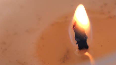 Slow-motion-macro-footage-of-orange-candle-flame-burning-and-flickering-surrounded-by-soy-wax