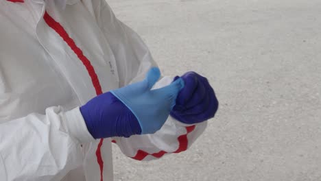 A-medical-worker-in-full-PPE-puts-on-a-double-layer-of-gloves-at-a-coronavirus-testing-center-during-the-COVID-19-pandemic