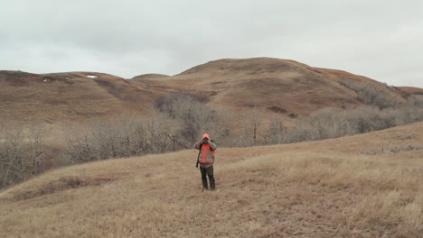 Male-Hunter-with-Orange-Jacket-and-baseball-cap-searching-for-big-game-with-his-binoculars-in-a-remote-wilderness-area