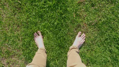 A-point-of-view-shot-looking-down-at-a-white-mans-feet-and-toes-standing-on-fresh-green-grass