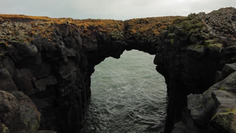 The-beautiful-black-arch-rock-formation-at-diamond-beach-by-the-sea-in-Iceland---wide-shot