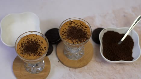 Sprinkling-chocolate-crumbs-on-dalgona-coffee,-top-view,-slow-motion