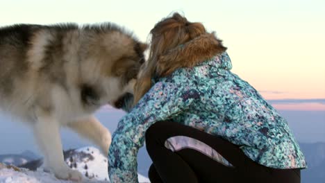 Junge-Frau-Streichelt-Hund-Auf-Berggipfel-Bei-Sonnenuntergang,-Pastellhimmel,-Zeitlupe