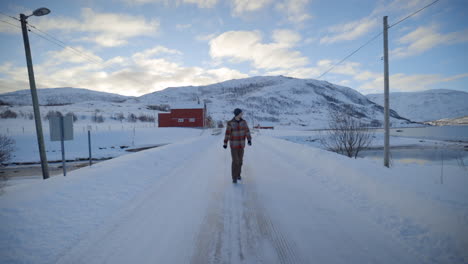 A-Man-Walking-Down-an-Empty-Snow-Covered-Road-in-a-Cold-Winter-Environment,-Static-Slow-Motion