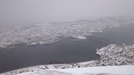 Wide-Pan-of-the-City-of-Tromso,-Norway-During-a-Snowstorm
