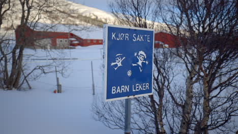 Drive-Slow-Children-at-Play-Road-Sign-in-Norwegian-with-a-Winter-Backdrop