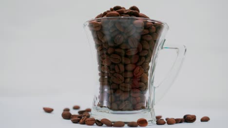 Studio-shot:-coffee-beans-in-and-around-a-clear-tall-coffee-mug-with-handle