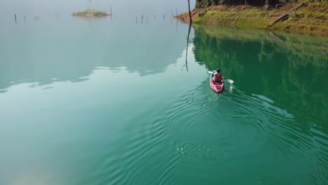 Hombre-En-Kayak-En-Un-Sereno-Lago-Cheow-Lan-En-El-Parque-Nacional-Khao-Sok-Bajo-El-Brillante-Día-Soleado-En-Tailandia