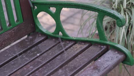 An-outdoor-park-bench-wet-from-the-snowfall-during-winter---close-up
