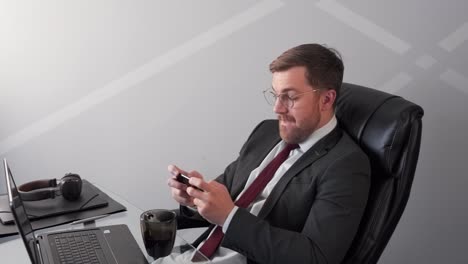 man-in-business-suit-playing-game-on-mobile-phone