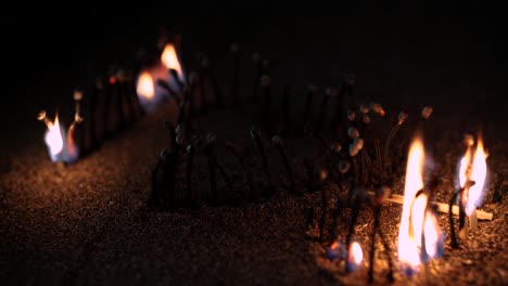 I-LOVE-YOU-sign-made-of-matchsticks-stuck-in-sand-burning-during-night