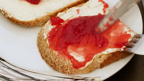 Studio:-delicious-strawberry-jam-being-spread-by-silver-knife-on-bread-and-butter