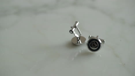 Close-up-to-a-pair-of-cufflinks-with-one-of-them-spinning-in-slow-motion