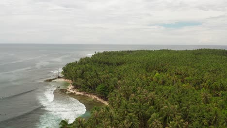 Aerial-parallax-shot-of-surfers-floating-in-palm-beach-bay-in-Indonesia