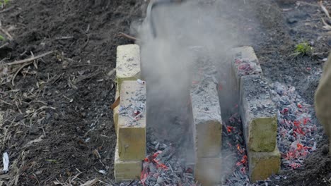 Shoveling-hot-coals-onto-bricks-on-a-backyard-oven