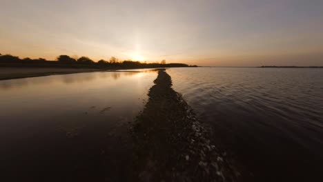 Aerial-drone-flight-along-beach-sandbanks-and-calm-lake-in-Veere-summer-sunset
