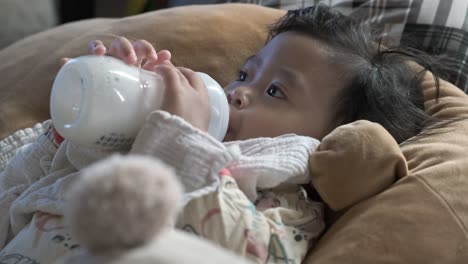 Asian-baby-girl-feeding-on-cows-milk-in-bottle-while-lying-down