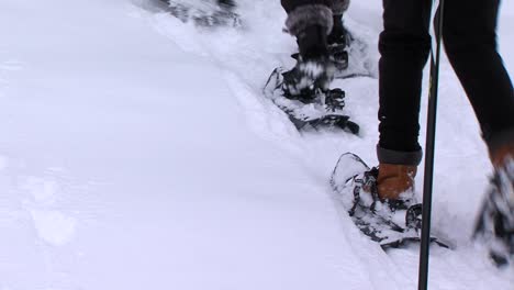 Children-with-snowshoes-on-feet-walk-in-deep-snow,-static-closeup