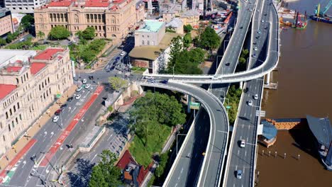 Aerial-View-Of-Vehicles-Driving-Along-The-Pacific-Motorway-And-Passing-By-Brisbane-River-On-A-Sunny-Day-In-Queensland,-Australia