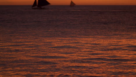 Dramatic-Slow-Motion-Tilt-Up-Shot-Of-Sea-Water-And-Sail-Boats-While-Sunset