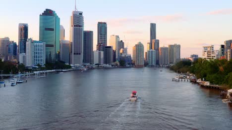 Motorboat-Sailing-At-Brisbane-River-Overlooking-The-High-rise-Buildings-At-Brisbane-CBD-At-Sunset-In-QLD,-Australia