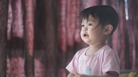 Cute-Asian-baby-girl-singing-and-clapping-hands-standing-up-at-home