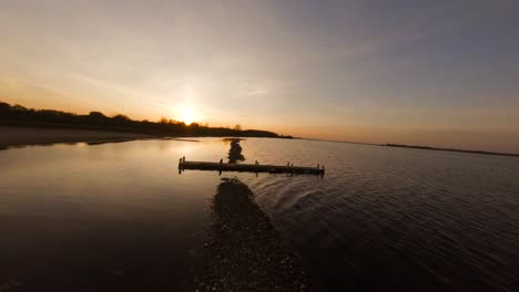 Aerial-drone-flight-over-sandbanks-in-calm-lake-reflecting-golden-Veere-sunset