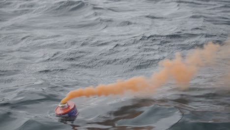 Eine-Orangefarbene-Rauchfackel,-Die-Beim-Testen-Von-Notsignalen-Verwendet-Wird,-Die-Während-Des-Nautischen-Trainings-Im-Patagonischen-Meer-Schwimmen---Nahaufnahme