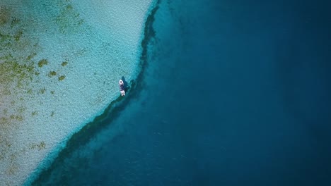 Aerial-view-of-a-small-fishing-boat,-floating-in-the-blue-Caribbean-sea,-at-Los-Roques-Venezuela
