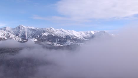 Weite-Aufnahme-Der-Majestätischen-Berglandschaft-Im-Winter,-Dunst-Und-Wolken-Ziehen-Vorbei