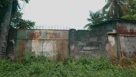 Rusty-gate-overgrown-by-nature-on-a-quiet-suburbs-in-Cadiz-City,-Negros-Occidental,-Philippines