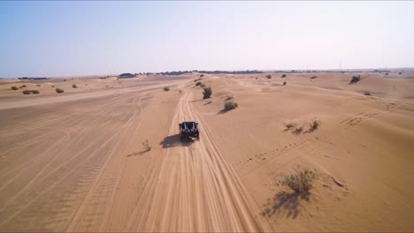 Black-4x4-truck-races-down-an-off-road-path-near-sand-dunes-in-the-desert-outside-of-Dubai,-UAE