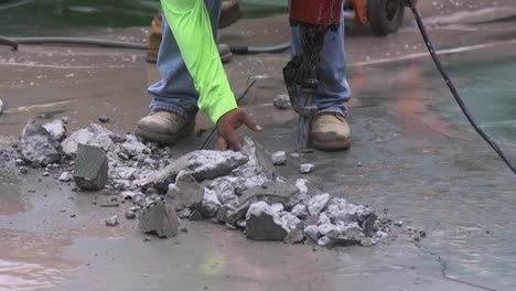 A-worker-with-a-jackhammer-reaches-down-to-move-the-rubble-and-debris-away-from-his-work-area