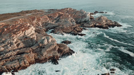Foamy-Sea-Waves-Splashing-On-The-Rocky-Shore-During-Summer-In-Vleesbaai,-Western-Cape,-South-Africa---Aerial-drone-shot