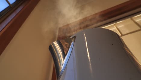Slow-motion-of-white-household-kettle-boiling-and-shaking-with-visible-steam-rising-to-ceiling