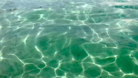 Zeitlupe-Einer-Kristallklaren,-Durchscheinenden-Und-Transparenten-Meerwasseroberfläche-Mit-Weißem-Sandboden-Und-Wellen