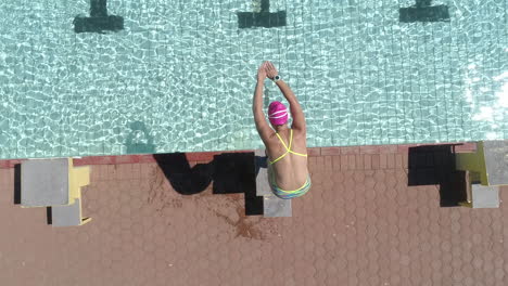 overhead-drone-footage-of-a-female-swimmer-diving-into-an-outdoor-pool-and-swimming-laps-as-part-of-her-triathlon-training
