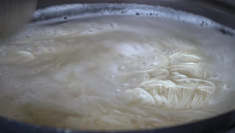 Cooking-boiling-Korean-rice-Pasta-in-big-metal-basin-pot-close-up