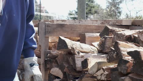 Man-in-blue-shirt-and-work-gloves-stacks-fire-wood-into-a-neat-pile