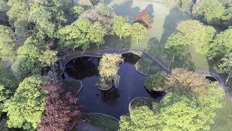 Deserted-peaceful-public-park-aerial-view-of-lush-lake-garden-above-treetop-orbit-right