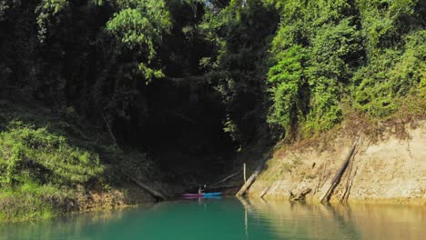 Hombre-En-Su-Kayak-Flotando-En-El-Agua-En-El-Lago-Tranquilo-En-La-Represa-Ratchaprapa,-Parque-Nacional-Khao-Sok,-Tailandia