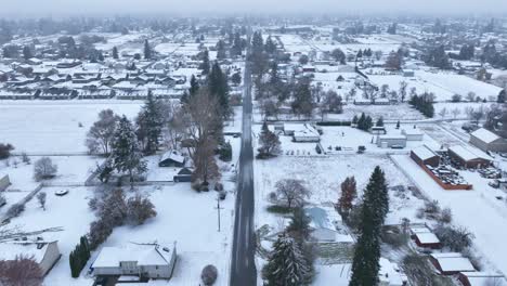 Aerial-view-looking-down-a-long-bare-road-in-rural-America-with-snow-covering-the-ground