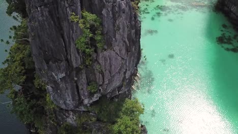 Tilt-Up-Aerial-View-of-Steep-Cliff-Dividing-Two-Majestic-Tropical-Lagoon-in-El-Nido,-Palawan-Island,-Philippines