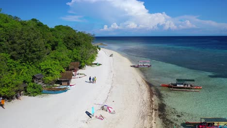 Banca-boats-near-Mantigue-Island-tropical-beach-in-the-Philippines,-backwards-aerial