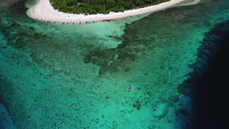 Banca-boat-approaching-Mantigue-Island-in-the-Philippines,-tilt-down-aerial