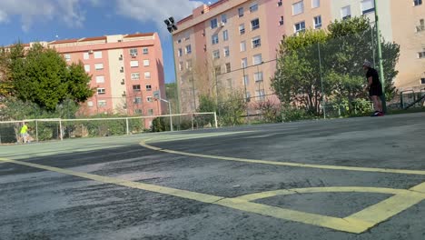 Junger-Mann-Spielt-Tennis-Im-Freien-Auf-Einem-Grünen-Tennisplatz-In-Der-Nähe-Eines-Wohngebiets