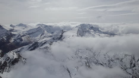 Aerial-panoramic-shot-of-Austrian-alps-with-snowy-and-iced-mountain-peaks-during-sunlight-at-sky